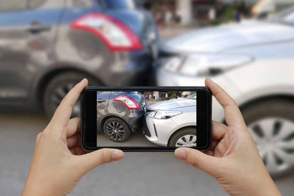 Persona fotografiando un accidente vehicular para reportarlo con su seguro de auto